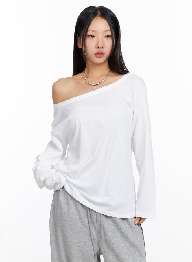 LEWKIN Relaxed Off-Shoulder Long Sleeve Top CO514 in white, front close-up on model, oversize cotton with asymmetric off-shoulder neckline, paired with grey sweatpants and layered necklace.