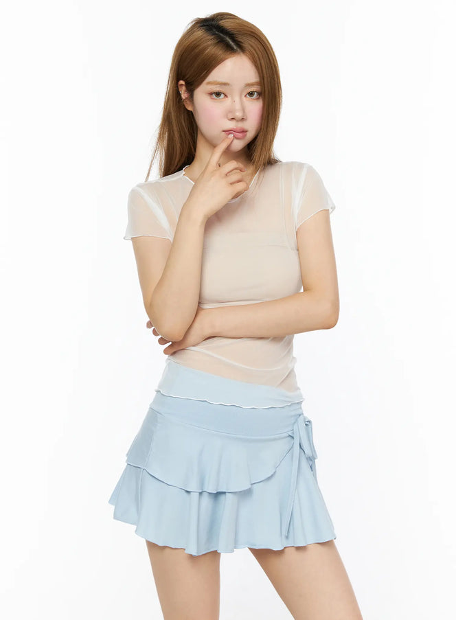 LEWKIN Sheer Short Sleeve Top CL501 White S/M front model shot, sheer mesh short sleeve top with lettuce hem, styled with light blue tiered mini skirt, thoughtful pose